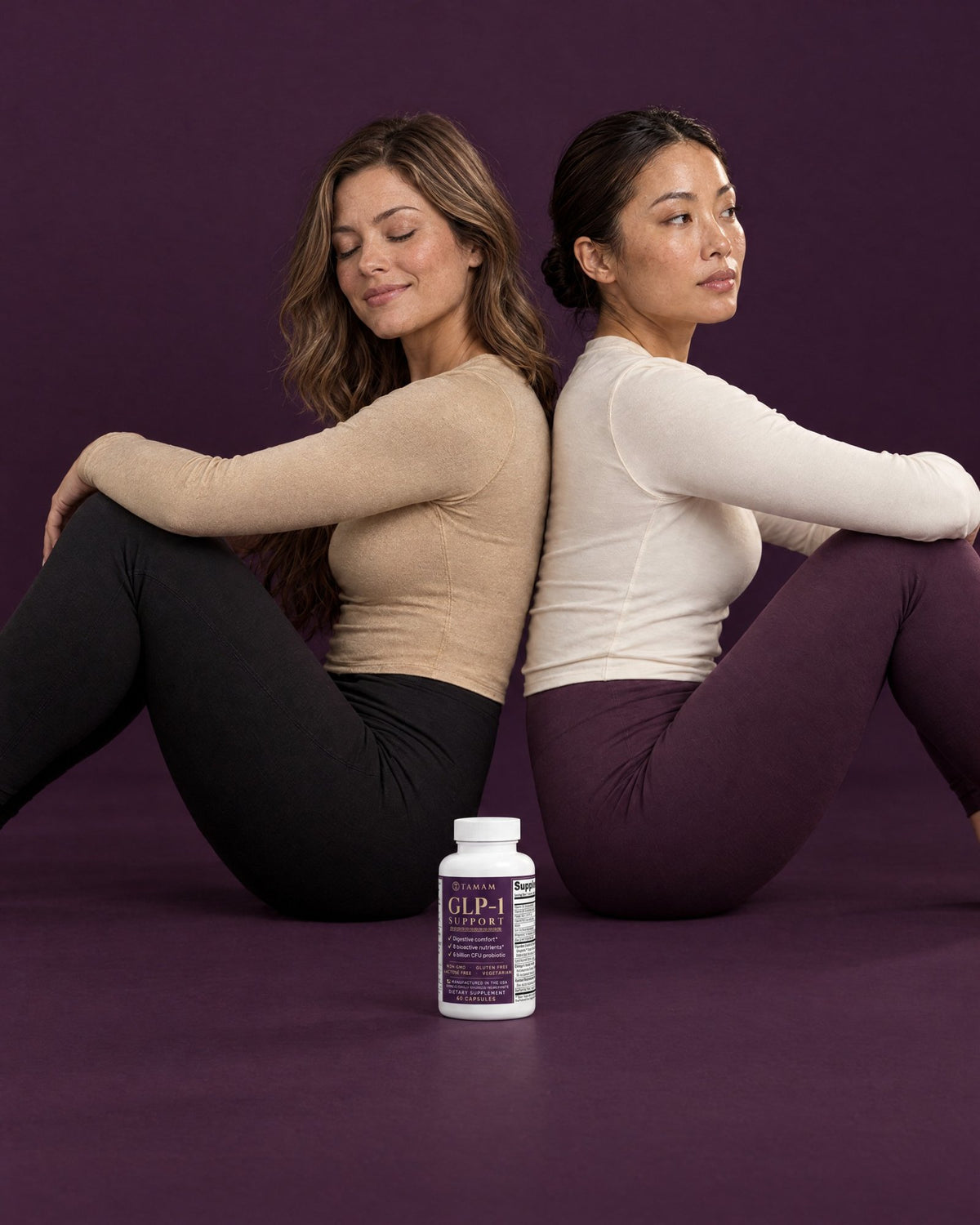 Two women sitting back to back with TAMAM