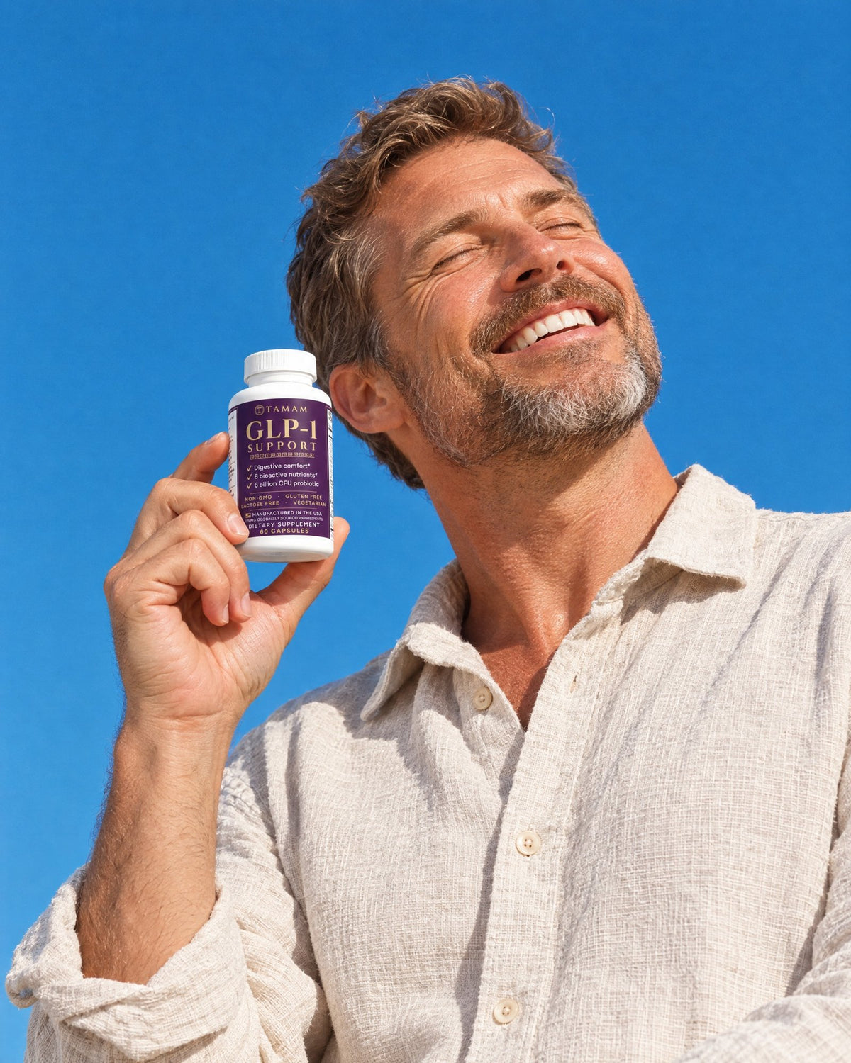 Man smiling in the sun holding TAMAM